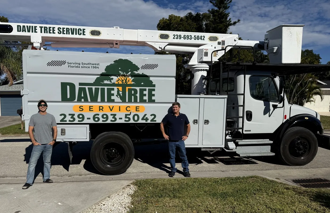Davie Tree Service owners standing with their branded bucket truck